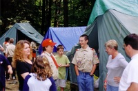 Two scouts in class A uniforms talking to each other, smiling.  Surrounding htem are 5 other people.