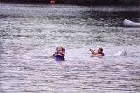 Two people in a canoe that has been swamped.  The canoe is just under the water surface.