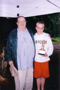 Two people standing on the camera.  The scout on the right is holding the Michael Dikant Award.