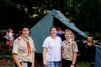 Three people smiling at the camera.  The two at the ends are wearing class A uniforms.