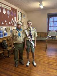 Two people smiling at the camera wearing class A uniforms.
