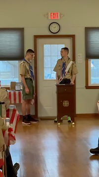 Two people in Class A uniforms.  The one on the right is behind a podium.
