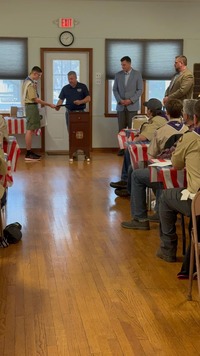 A politician giving Anthony a stack of papers from behind a podium.
