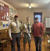 Three people smiling for the camera.  The two on the left are wearing Class A Uniforms