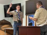 Two people in class A uniforms.  Liam is on the left giving the scout sign.
