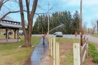 One scout trying to spray another scout with a hose.  The spray from the hose is not going to reach.