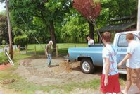 Mark Brockley is staring at the hole, filling it with water from a hose.  Brett and Rob are walking towards him in front of a blue pickup truck.  Seth's dad is standing behind the truck.