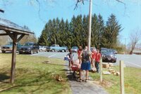 Six people standing around a cement mixer, looking at it.