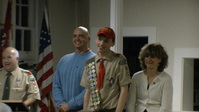 Three people smiling at the camera.  The person in the middle is wearing a Class A uniform.