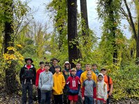 Group picture featuring 12 scouts and scoutmaster Jeff Brewer, standing to the left.  There are trees in the background.