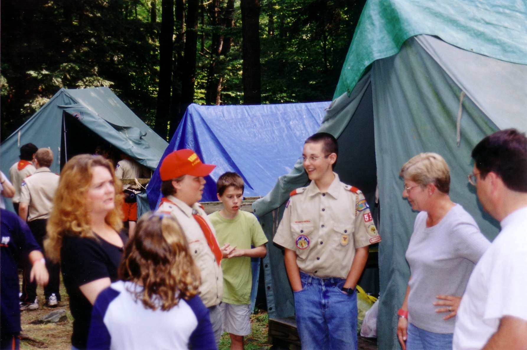 Two scouts in class A uniforms talking to each other, smiling.  Surrounding htem are 5 other people.