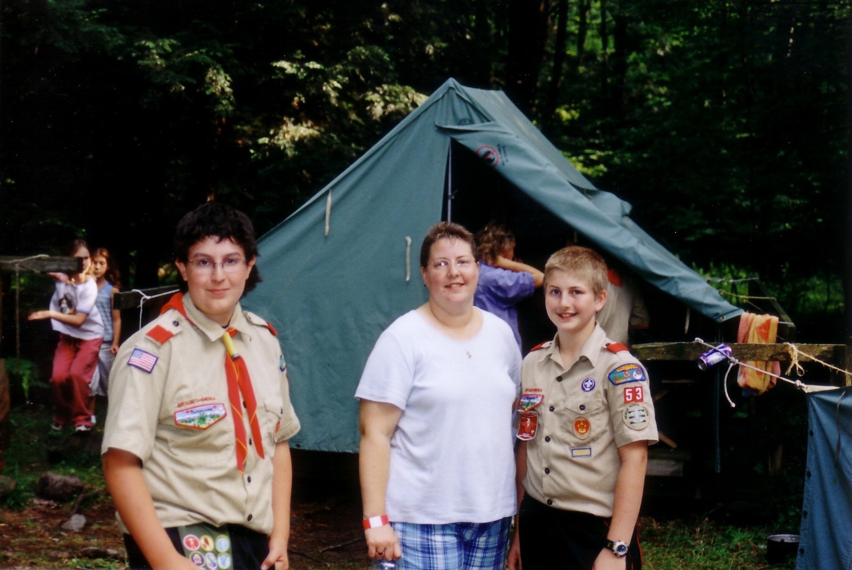 Three people smiling at the camera.  The two at the ends are wearing class A uniforms.