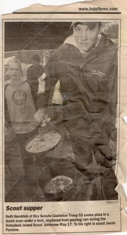 Scout Supper: Seth Hendrick of Boy Scouts Castleton Troop 53 cooks pizza in a dutch oven under a tent, sheltered from pouring rain during Schodack Island Scout Jamboree May 17.  To his right is scout Jacob Parslow.