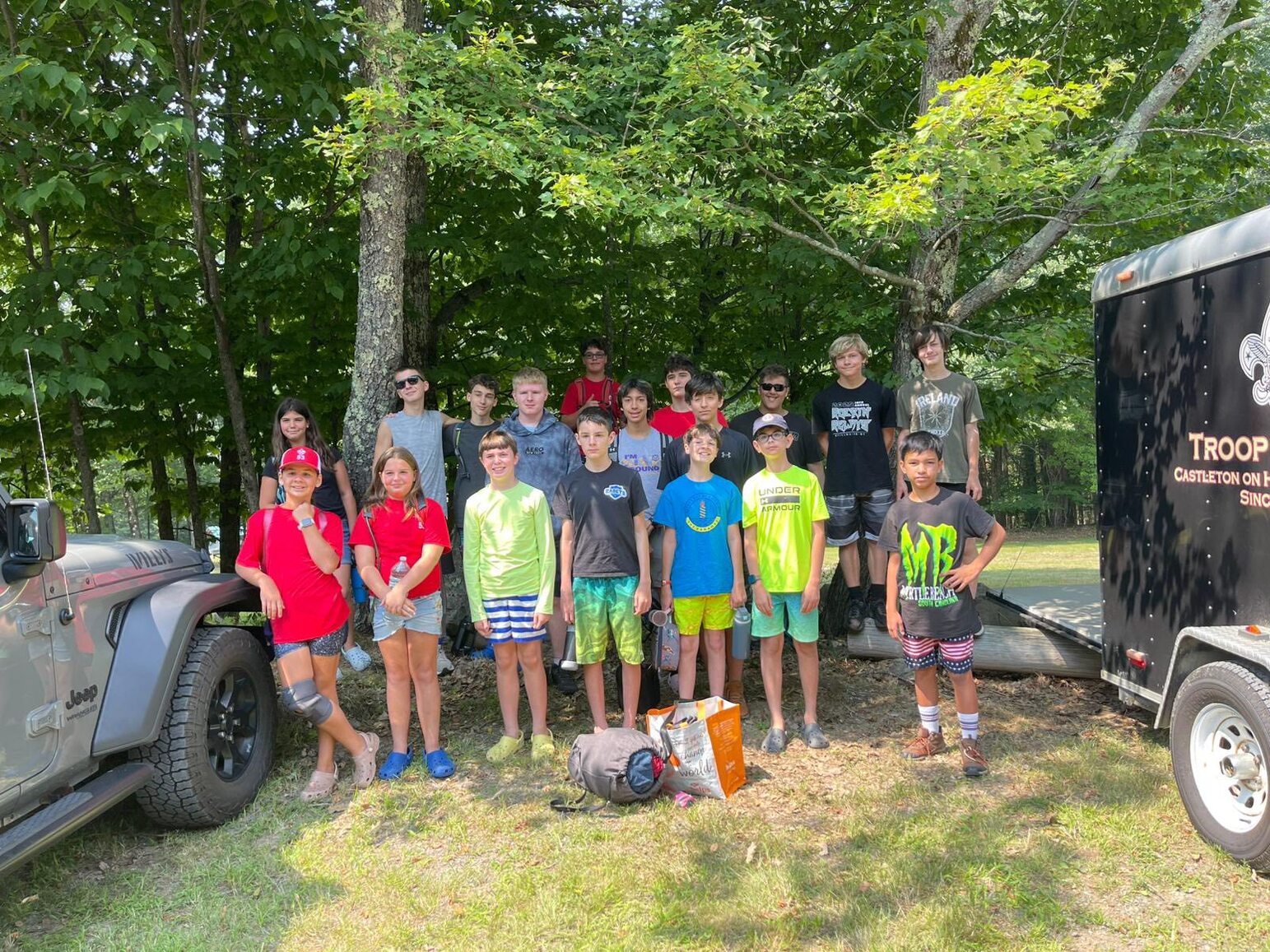 Group photo!  18 scouts are standing next to the troop trailer, which on on the right.