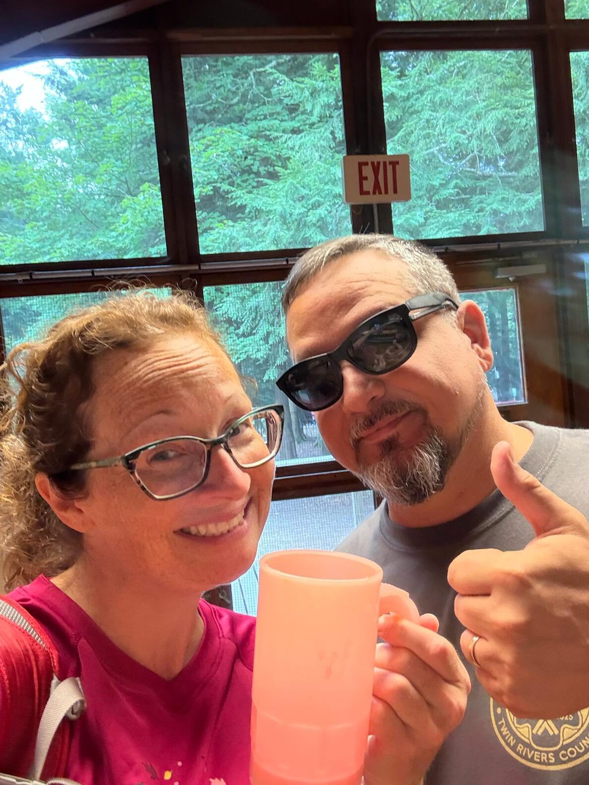 Two adult leaders giving a selfie to the camera.  One is holding up a mug, the other is giving a thumbs-up sign.