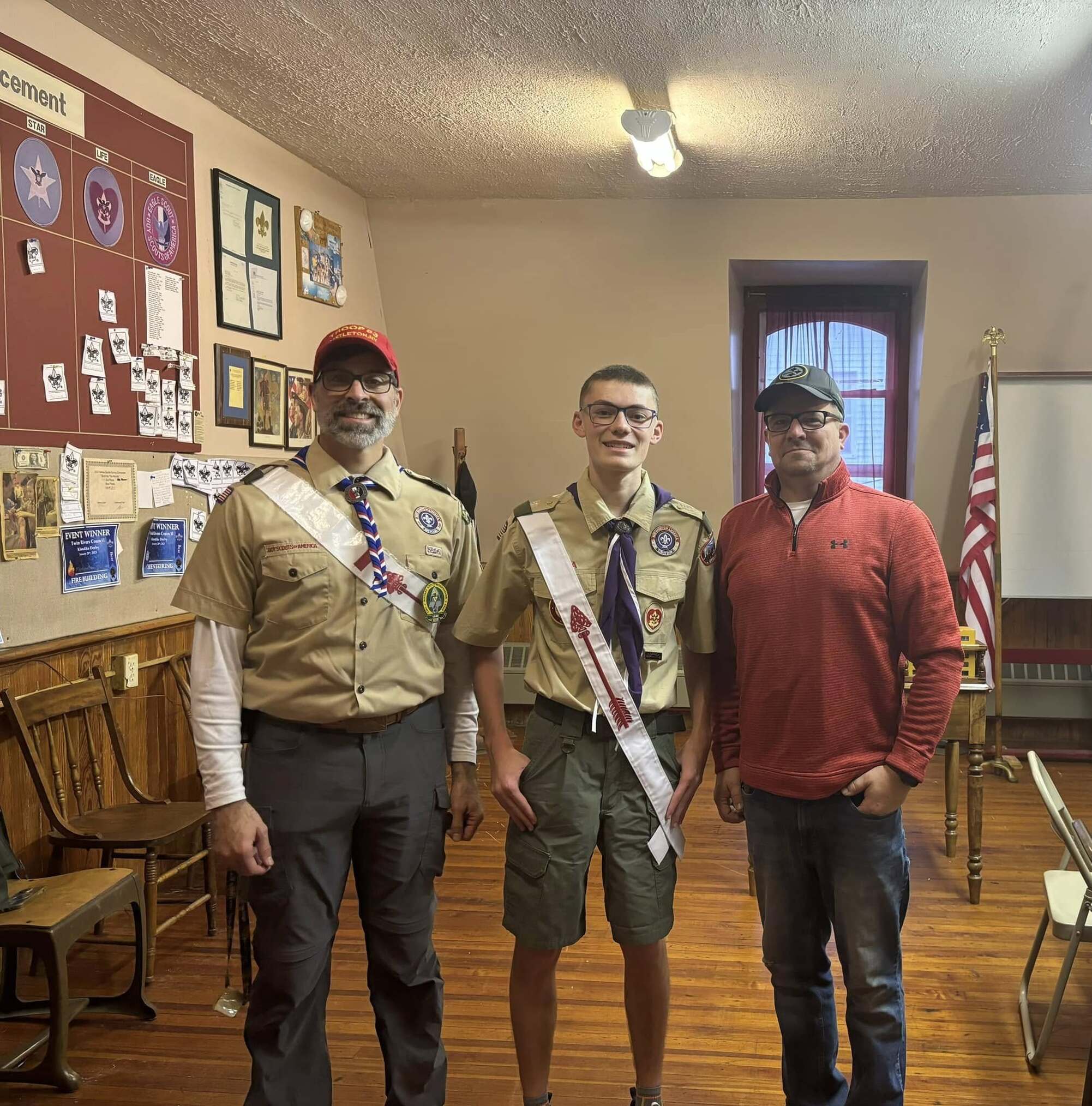 Three people smiling for the camera.  The two on the left are wearing Class A Uniforms