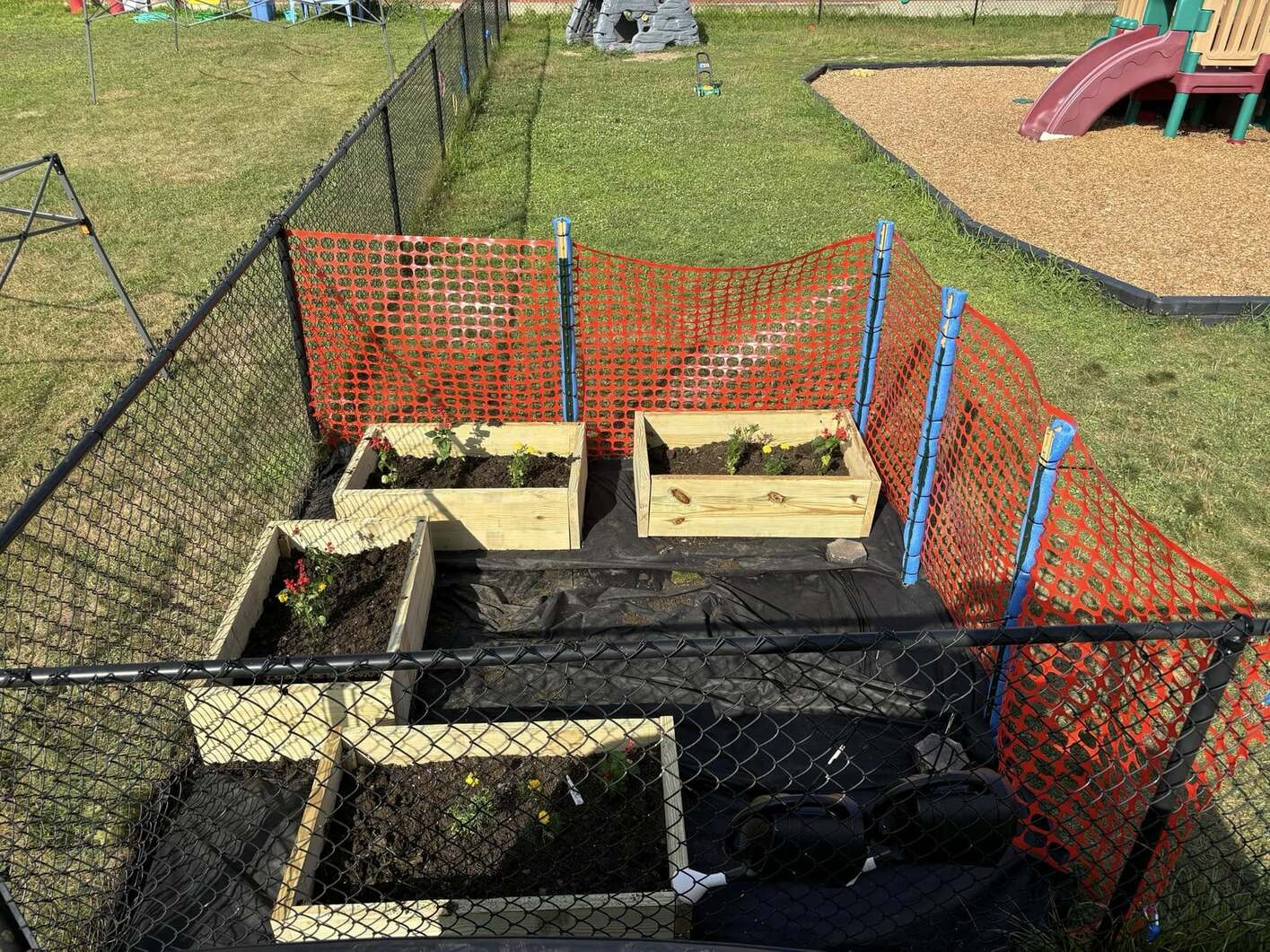 The completed garden boxes with soil and small flowers in them.
