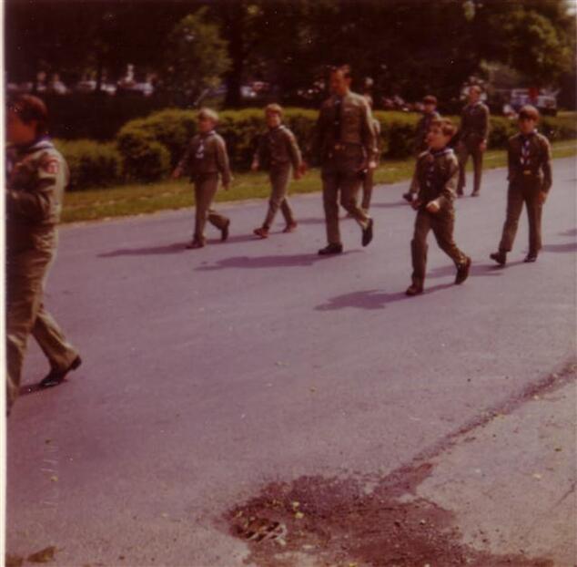 Scouts marching down the street, heading left.