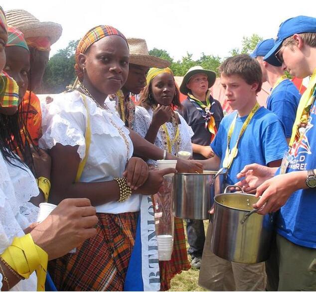 Matt McKnight holding a pot, another person is scooping something out of it.